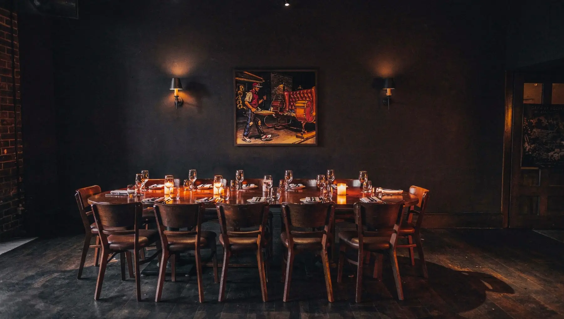 A large private dining room, a single long candlelit table set for a party, leather booths either side.